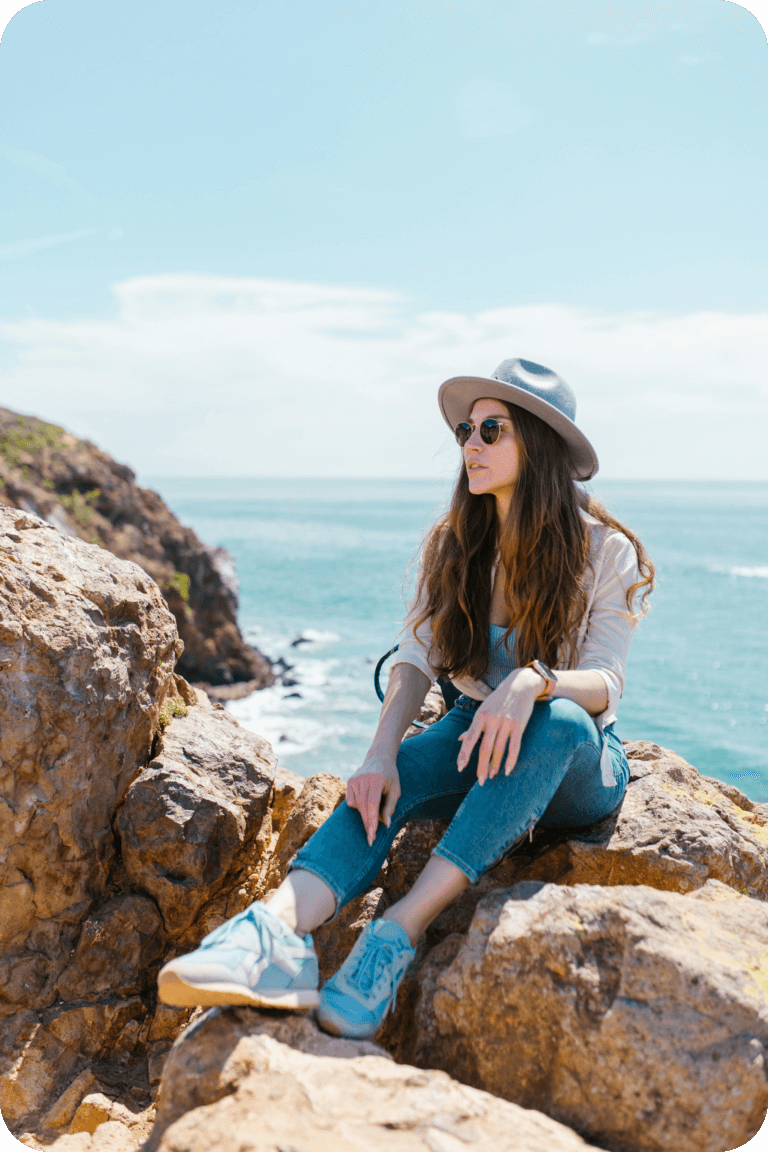 Femme, future investisseur, assise sur un rochet au bord de mer